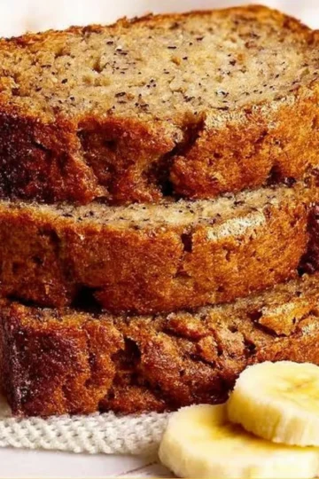 Loaf of classic banana bread with ripe bananas and walnuts on a wooden board