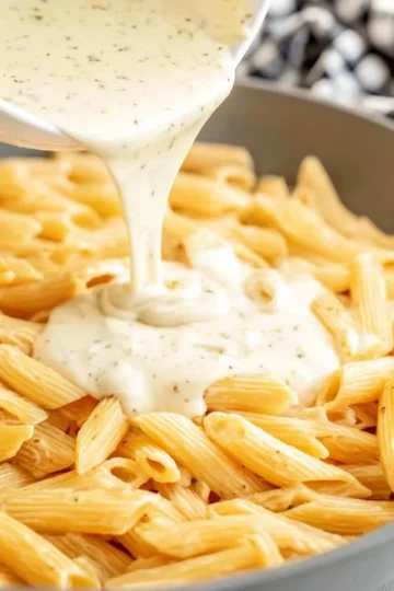 Plate of creamy white sauce pasta garnished with fresh herbs