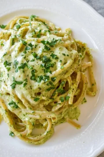 Plate of easy creamy pesto pasta with fresh basil and parmesan cheese
