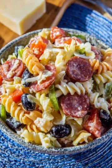 Colorful Italian pasta salad with fresh vegetables and dressing.