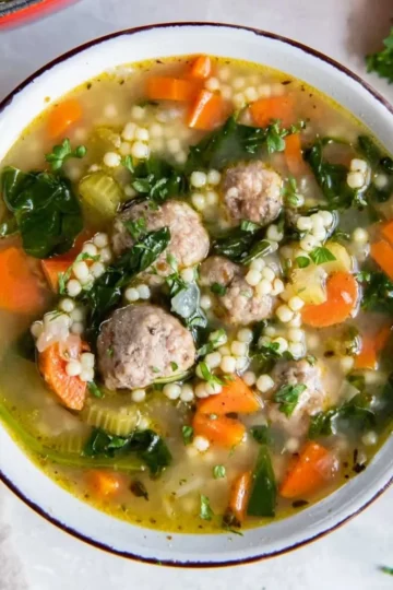 Bowl of Italian Wedding Soup with meatballs and vegetables.