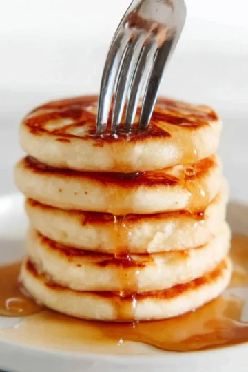 Delicious mini silver dollar pancakes stacked on a plate with syrup