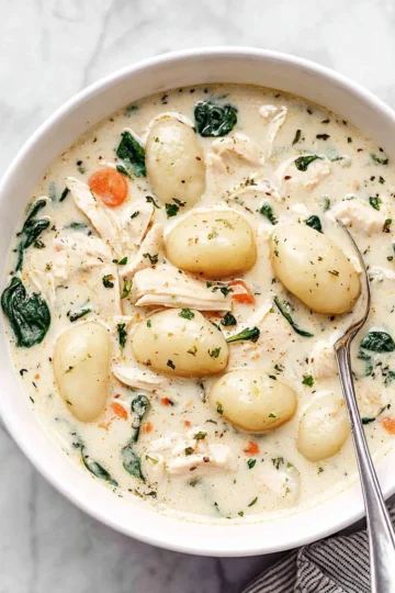 Bowl of Olive Garden style Chicken Gnocchi Soup with herbs and bread