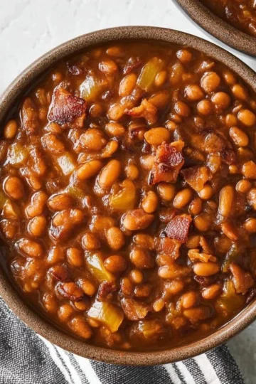Delicious smoky baked beans served in a bowl with barbecue sauce and herbs