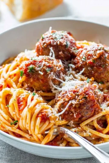 Delicious plate of spaghetti and meatballs topped with fresh basil and parmesan cheese