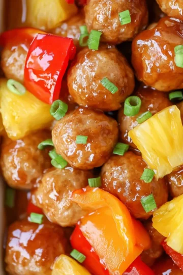 Sweet and Sour Meatballs in a serving dish with colorful sauce and garnish
