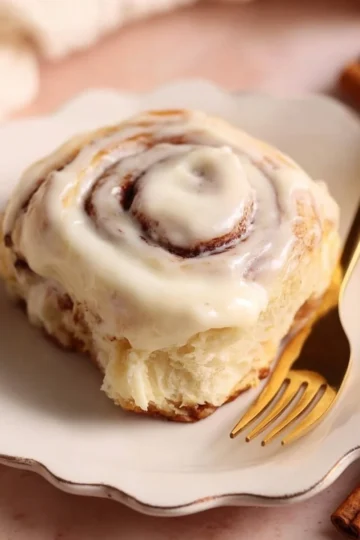 Delicious soft cinnamon rolls topped with creamy icing on a plate