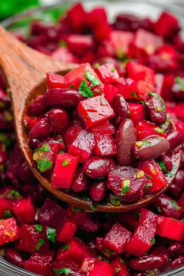 A vibrant beet salad with beans served on a plate, garnished with fresh herbs.