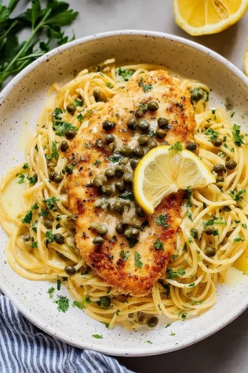 Plate of Chicken Piccata with lemon sauce and capers, garnished with parsley.