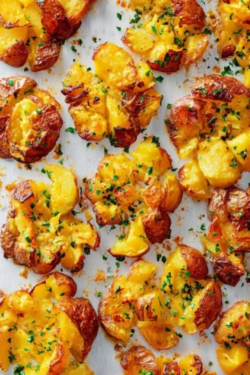 Crispy smashed potatoes baked to golden perfection, served on a plate.