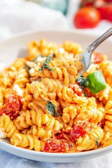 Delicious feta tomato pasta dish garnished with fresh herbs