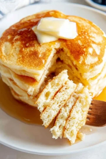 Fluffy Greek yogurt pancakes stacked on a plate with syrup and berries