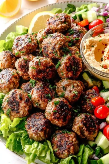 Plate of Greek meatballs (Keftedes) garnished with herbs and lemon.