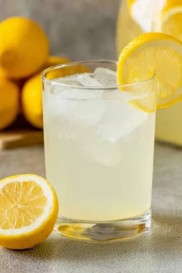 A refreshing glass of homemade lemonade with lemon slices and mint leaves.