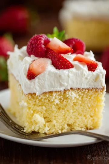 Delicious slice of Three Milks Cake topped with whipped cream and fruits